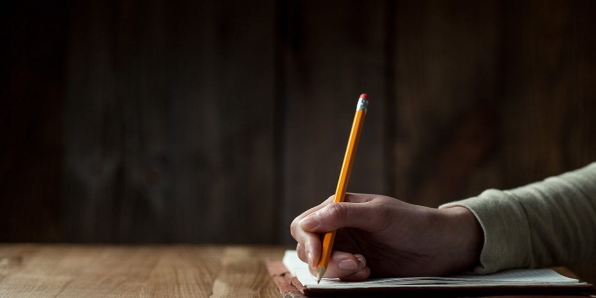 Hand writing notes with a pencil in a dark room