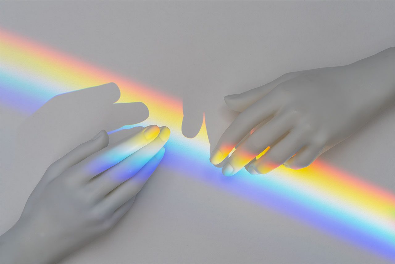 Abstract hands touching with a rainbow light
